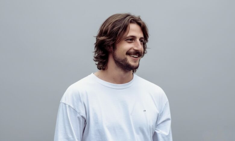 Portrait of Milo Arthur Johnson standing outdoors, looking away from the camera with a neutral expression.”